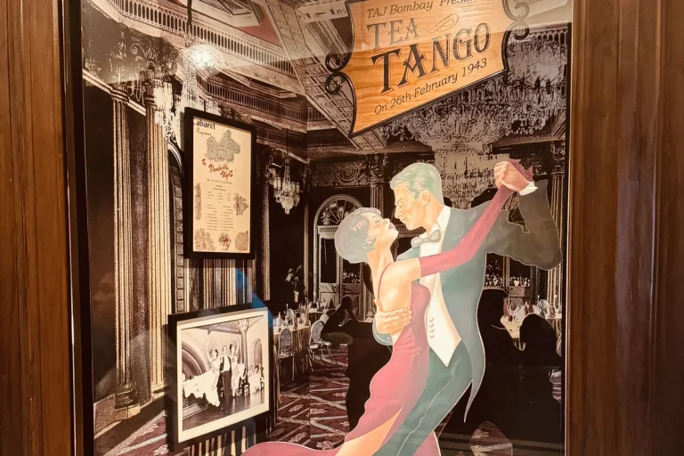 A display window at the Taj Mahal Palace containing vintage photographs and a menu card from the 1943 tea and tango evenings.